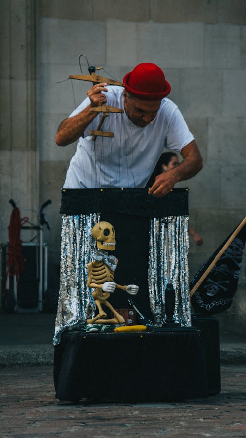 Free Photo of a Man in a White Shirt Controlling a Skeleton Puppet Stock Photo