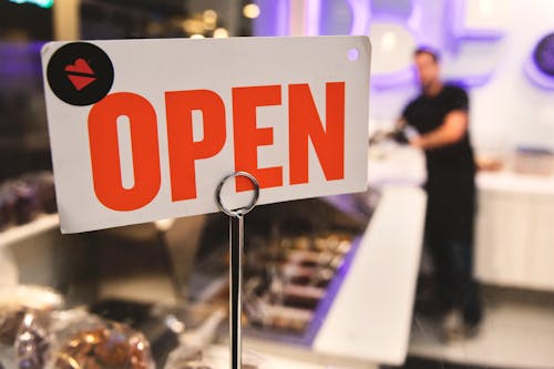 Free Shallow Focus Photography of Red and White Open Signage Near Man Wearing Black Shirt Stock Photo