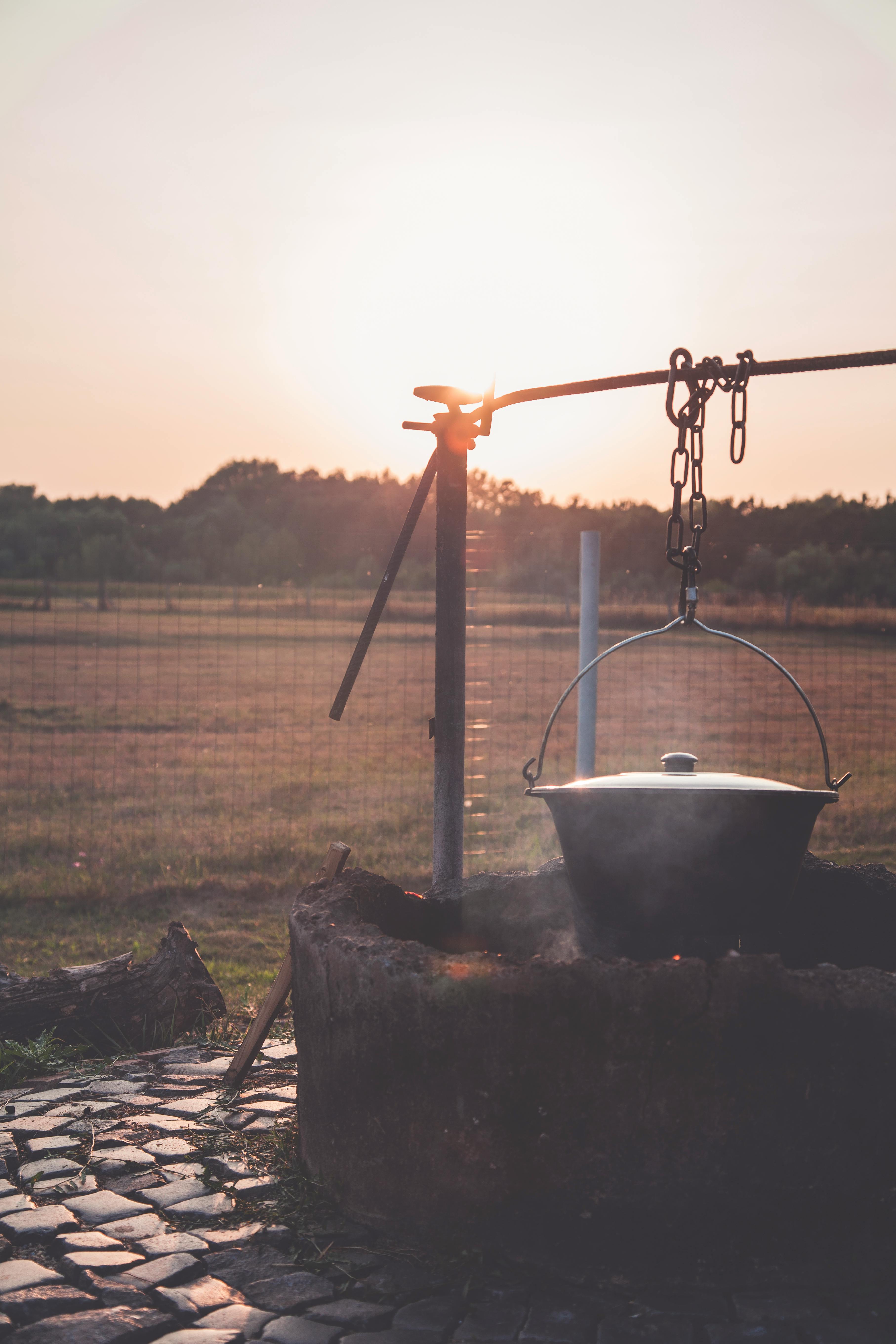 乡村日落风景优美，农场里的明火上架着一口锅