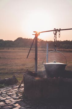 乡村日落风景优美，农场里的明火上架着一口锅
