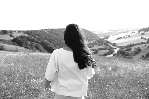 Grayscale Photo of a Woman Standing on a Grass Field