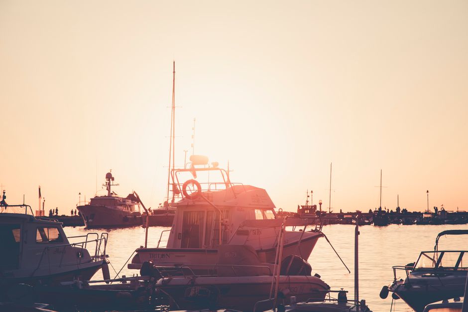 A peaceful marina scene at sunset with boats silhouetted against the glowing sky.