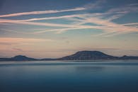 日出时分，柔和的天空下，海洋与山脉的景色宁静祥和