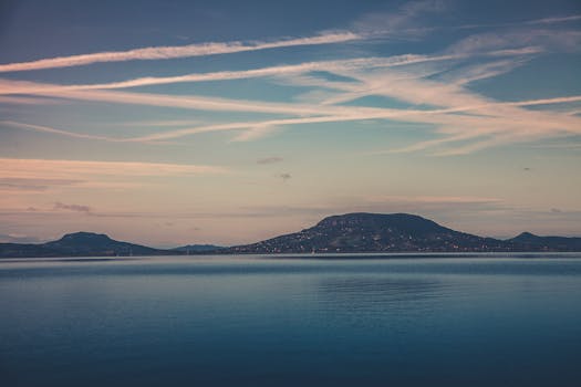 日出时分，柔和的天空下，海洋与山脉的景色宁静祥和