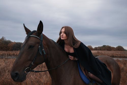 Photo of a Woman with Brown Hair Riding a Brown Horse