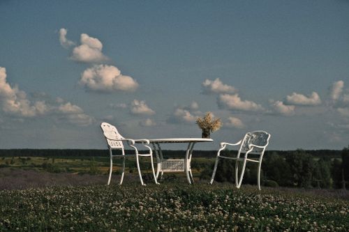 Free White iron chairs and table set amidst a peaceful field, perfect for outdoor relaxation. Stock Photo