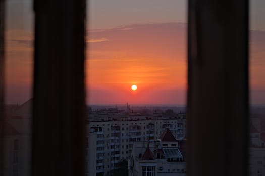A serene sunset view over a cityscape framed perfectly by window edges, creating a peaceful ambiance.