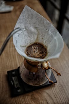 Top view of coffee being brewed in a Chemex on a wooden counter.