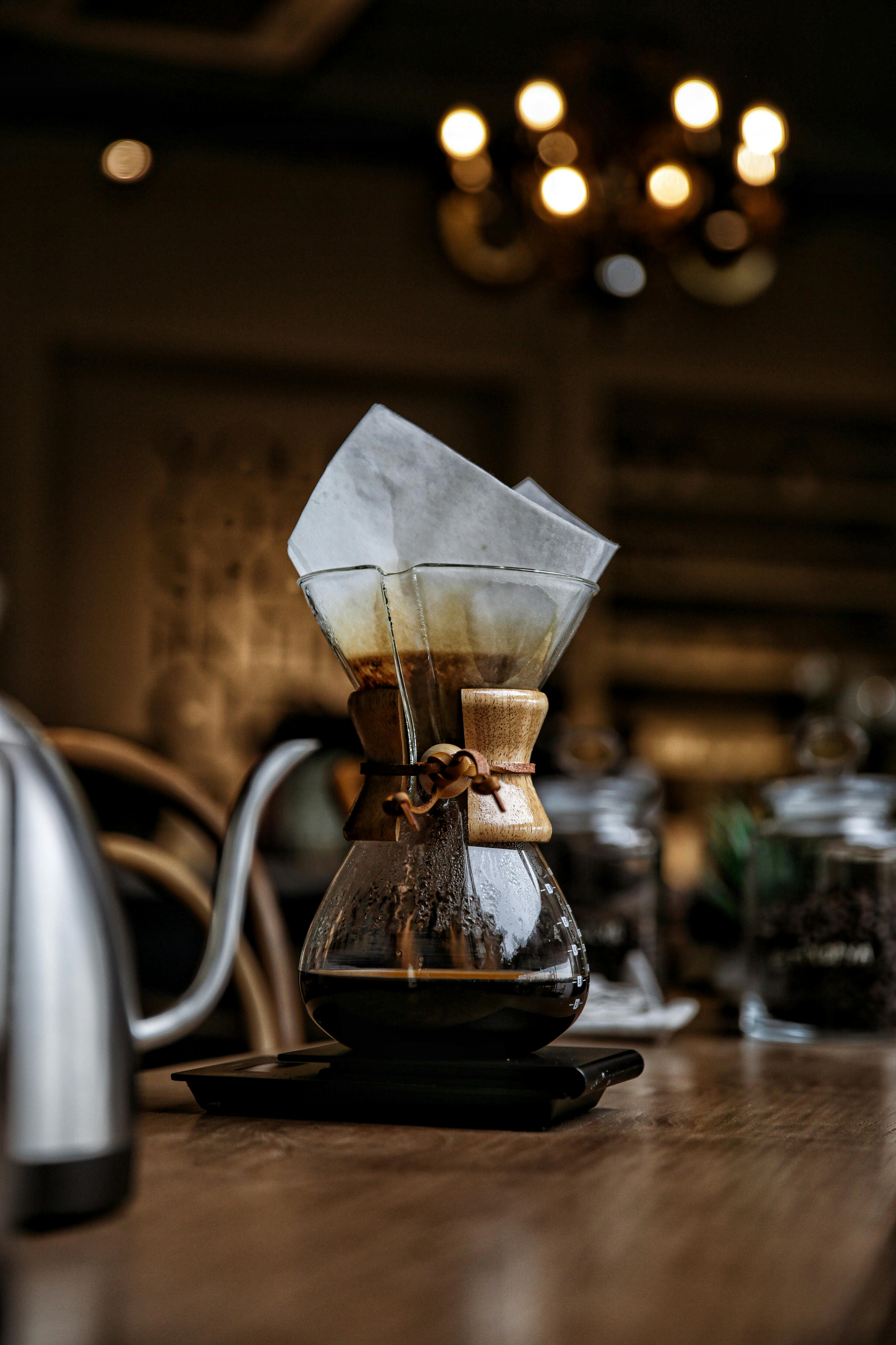 Creative close-up of a coffee dripper in a warm cafe setting, featuring rustic and vintage elements.