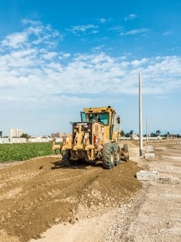 A powerful tractor working on a construction site under a bright blue sky, highlighting heavy engineering equipment.