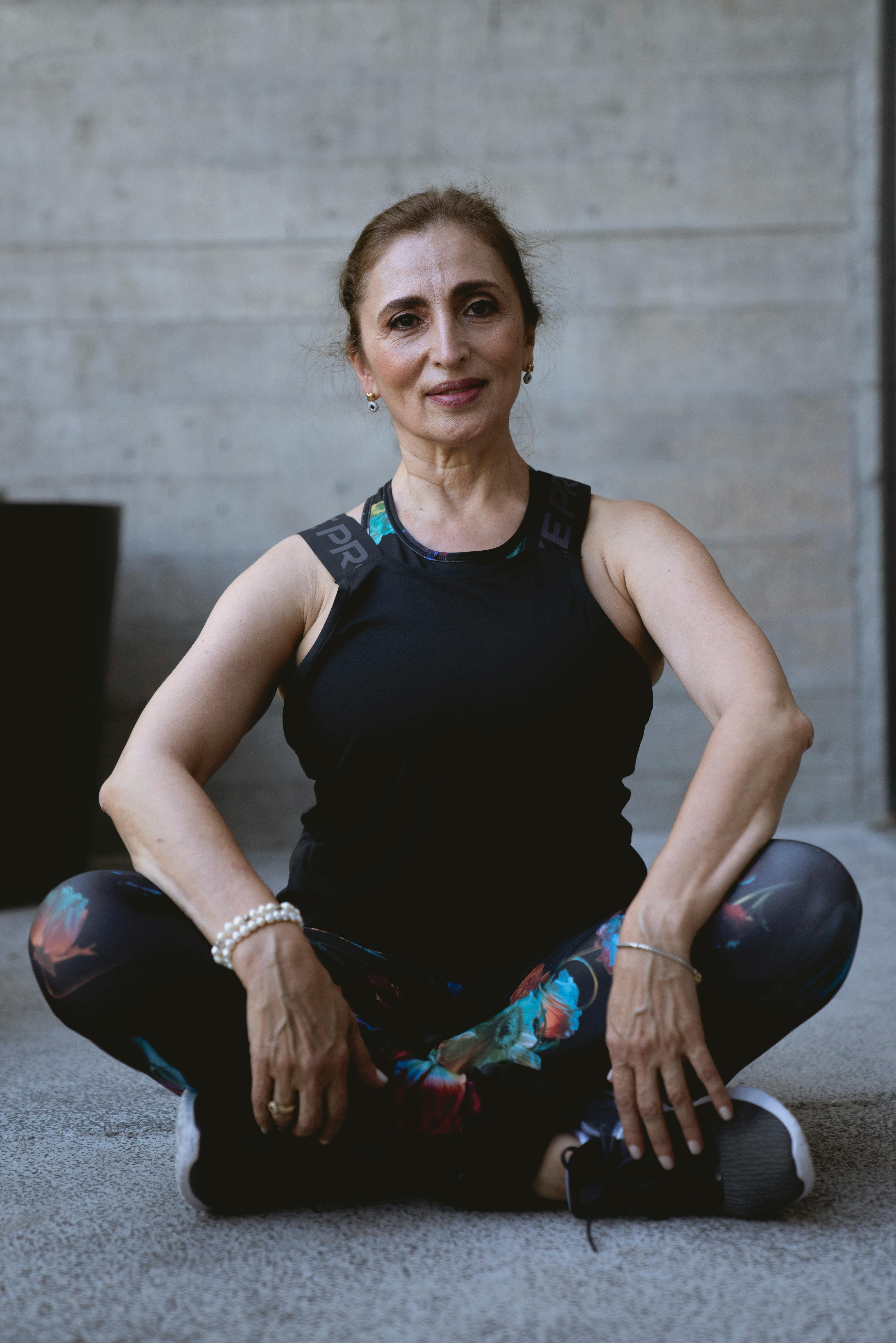 Elderly Caucasian woman in sportswear sitting indoors reflecting positive aging and fitness.