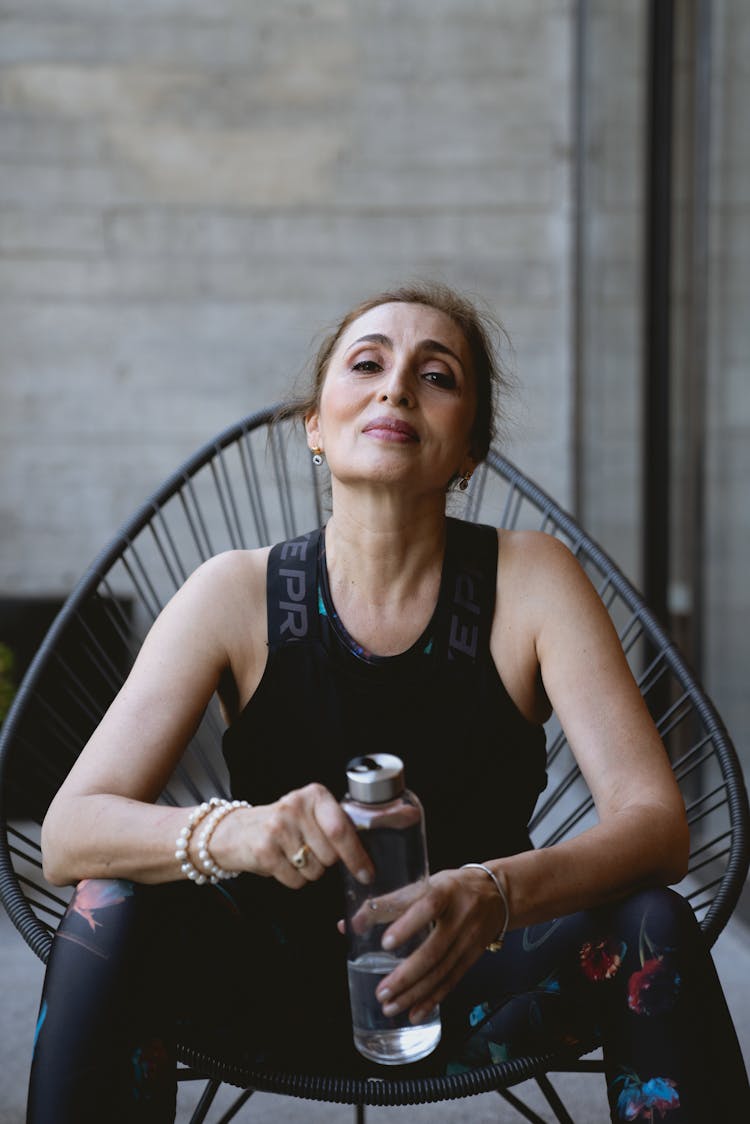 Woman In Black Tank Top Sitting On Black Metal Chair Holding Cup