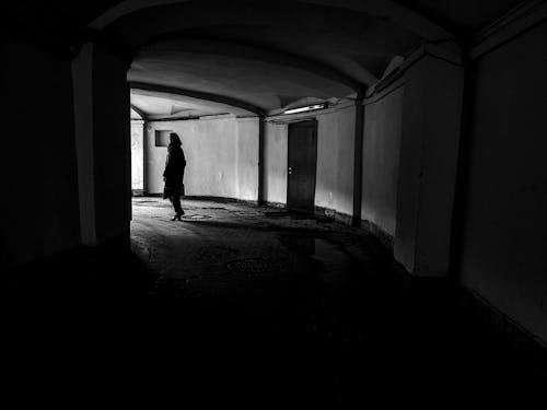 Monochrome Shot of a Person Standing at the End of a Hallway 
