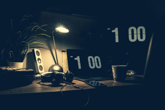 A dimly lit desk with a laptop and headphones — photo by Julien Bachelet on Pexels