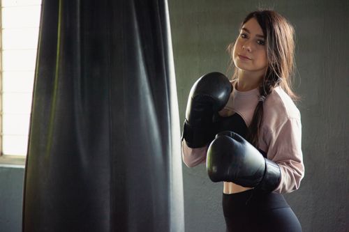 Free A young woman with boxing gloves trains in an indoor gym, focused and determined. Stock Photo