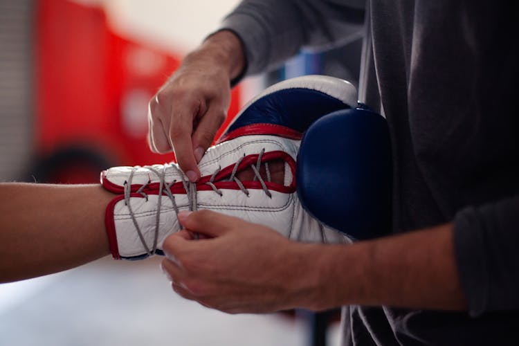 A Person Tying The Laces Of A Boxing Glove 