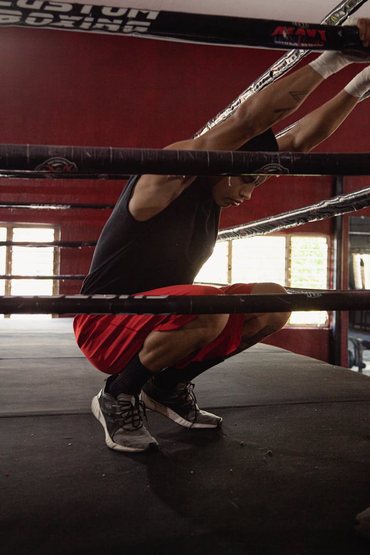 A Man In Black Tank Top Sitting Inside The Boxing Ring