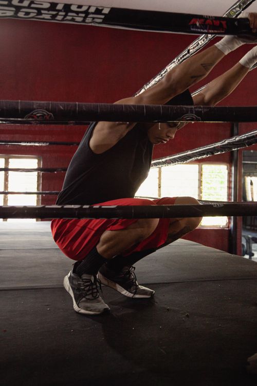 Free Athlete in red shorts taking a break in a boxing ring, indoors. Stock Photo