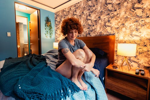 Free A Woman in Gray Shirt Sitting on the Bed Stock Photo