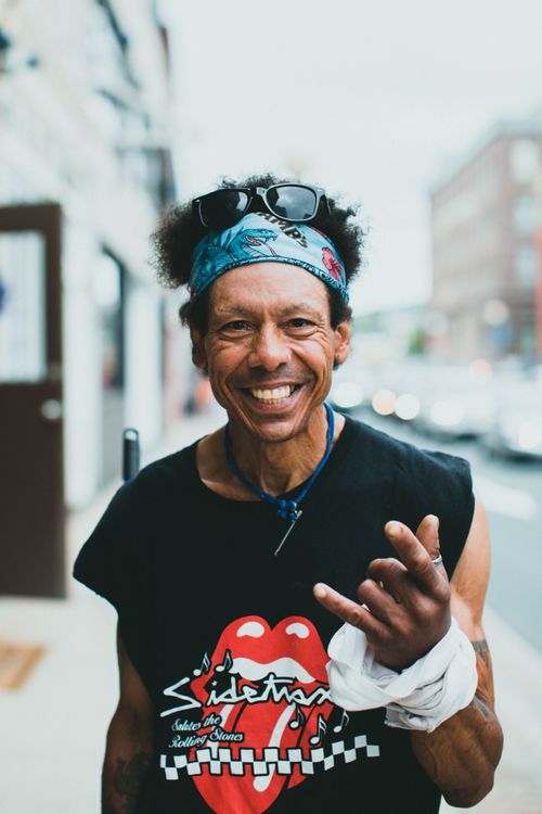 Free A cheerful man with a bandana and sunglasses showing a rock gesture on an urban street. Stock Photo