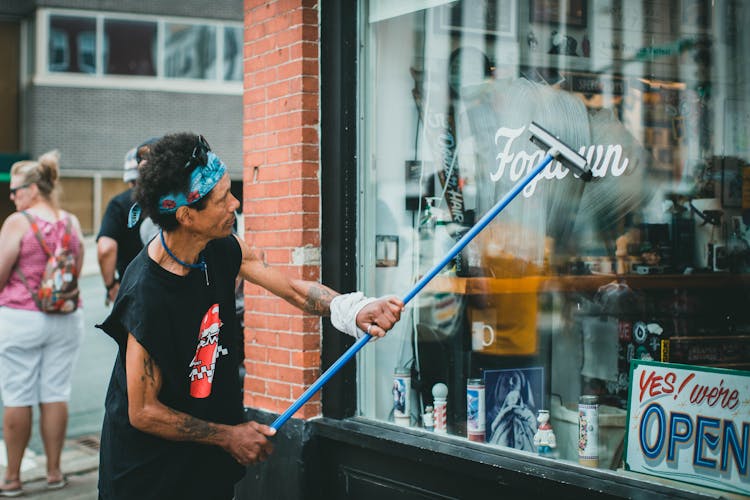 A Man In Black Tank Top Cleaning The Glass Window