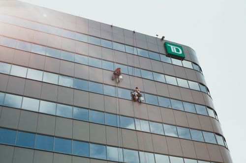 Free Workers clean the glass facade of a skyscraper, highlighting urban labor and architecture. Stock Photo