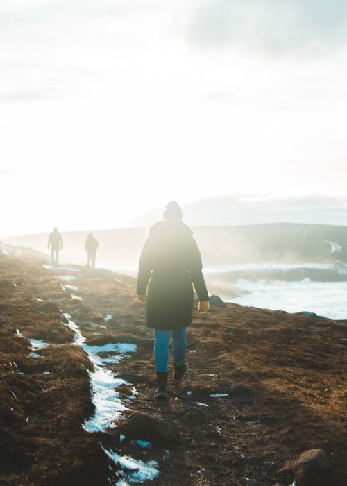 Free Person walking along a wintery coastal path with ocean waves in the background. Stock Photo