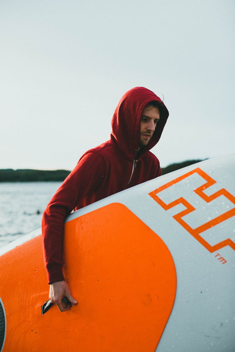 Man In Red Hoodie Carrying A Paddle Board