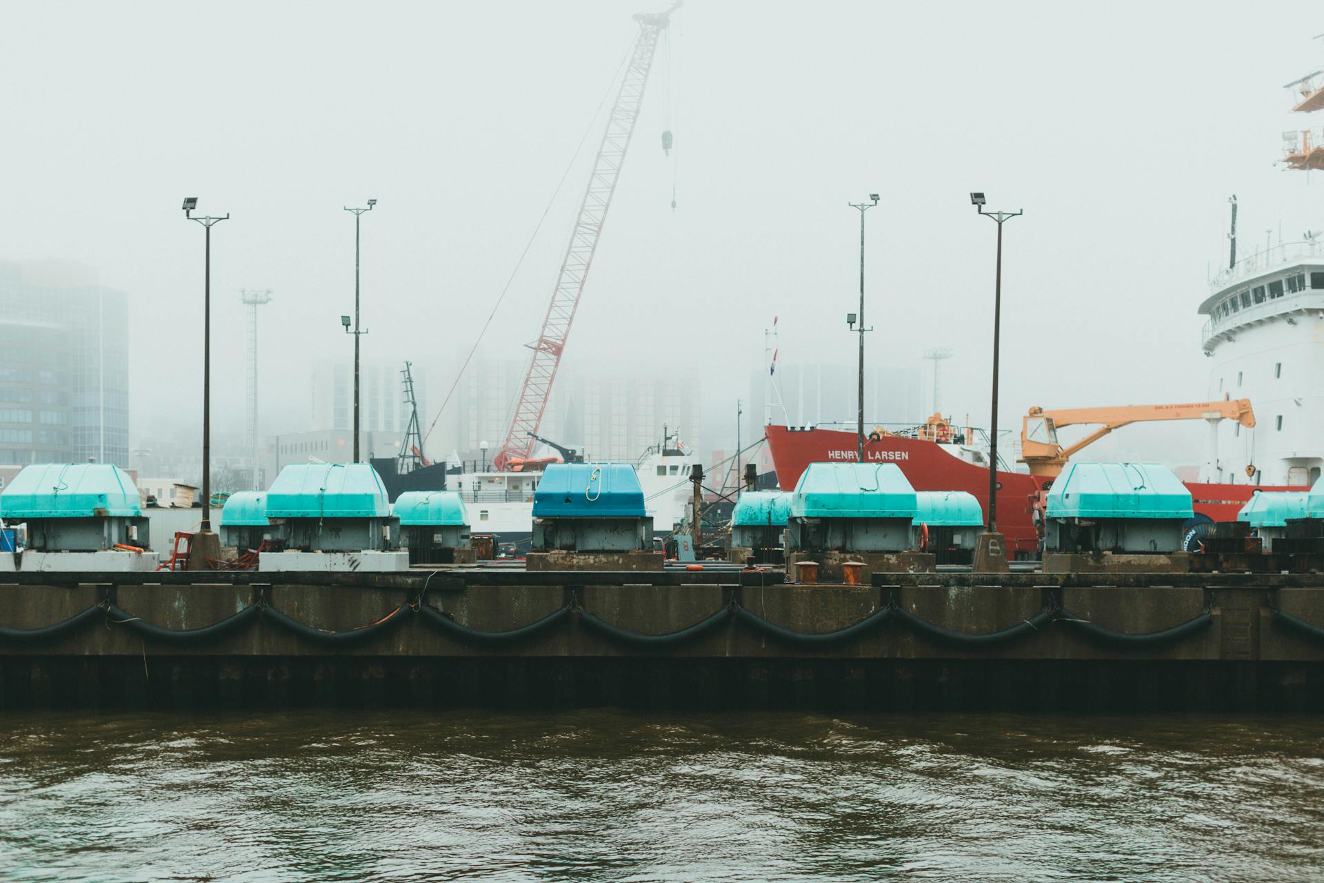 A foggy dock scene featuring large ships and cranes in a harbor setting.
