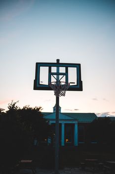 A basketball hoop silhouette against a vibrant dusk sky, capturing the essence of outdoor sports.