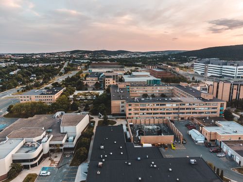 Free Aerial drone shot of an urban landscape featuring multiple buildings and roads during sunset. Stock Photo