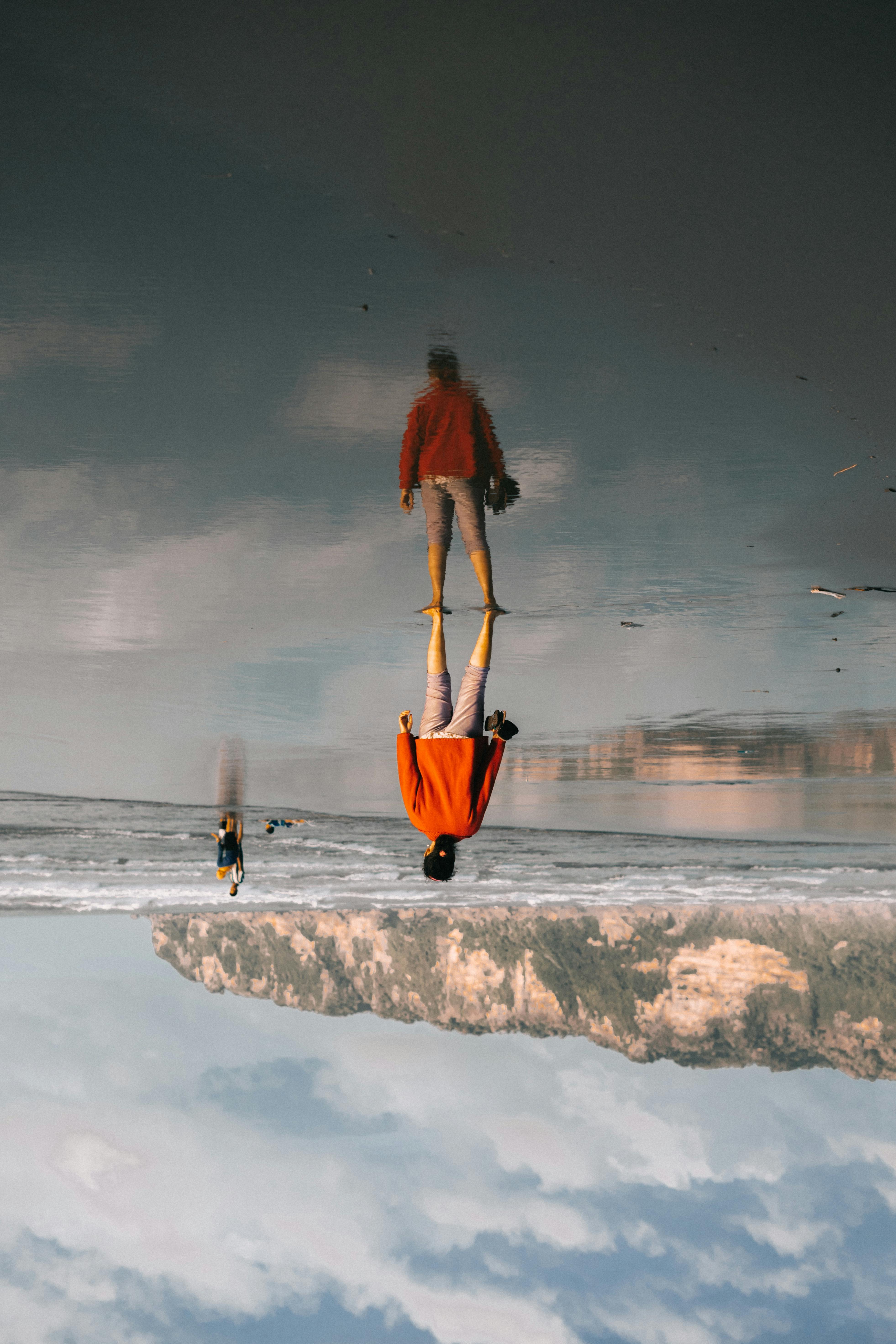 冬季，人们在平静的海滩上反思，呈现出一种颠倒的景象