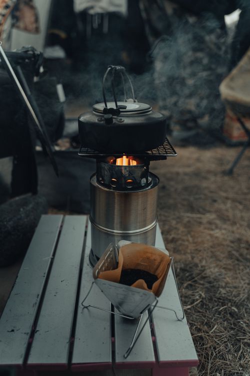 Free Outdoor scene of a campfire stove with a coffee brewer and kettle, creating a warm atmosphere. Stock Photo