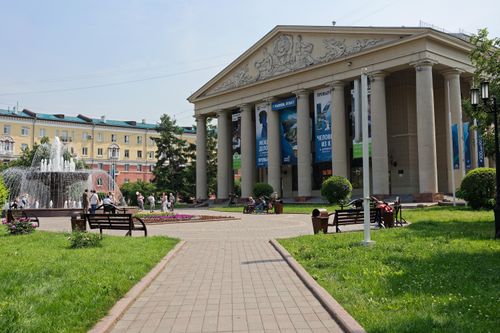 Free Elegant urban scene with a classical building and vibrant park setting featuring a fountain. Stock Photo