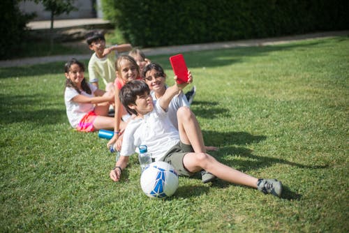 Children Taking a Groupfie while Sitting on the Grass