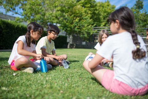 Free Group of children playing outside on grass, enjoying a sunny day. Stock Photo