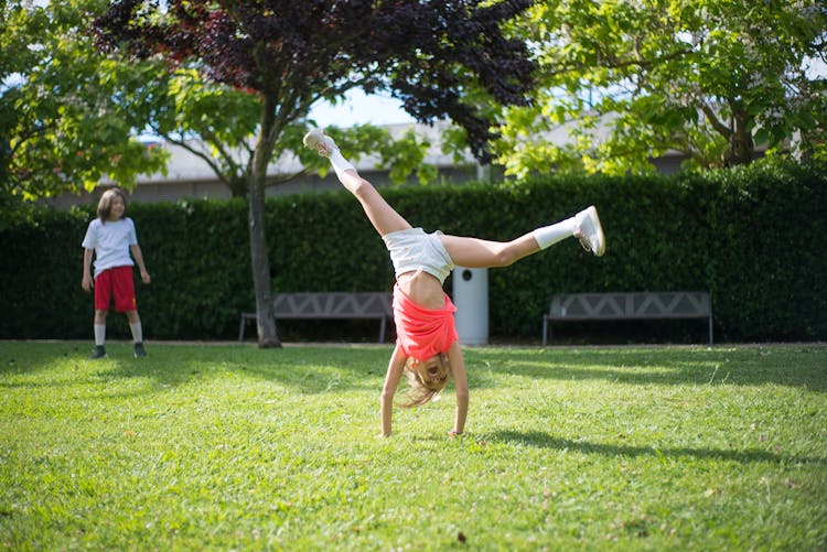 Girl Tumbling On Green Grass