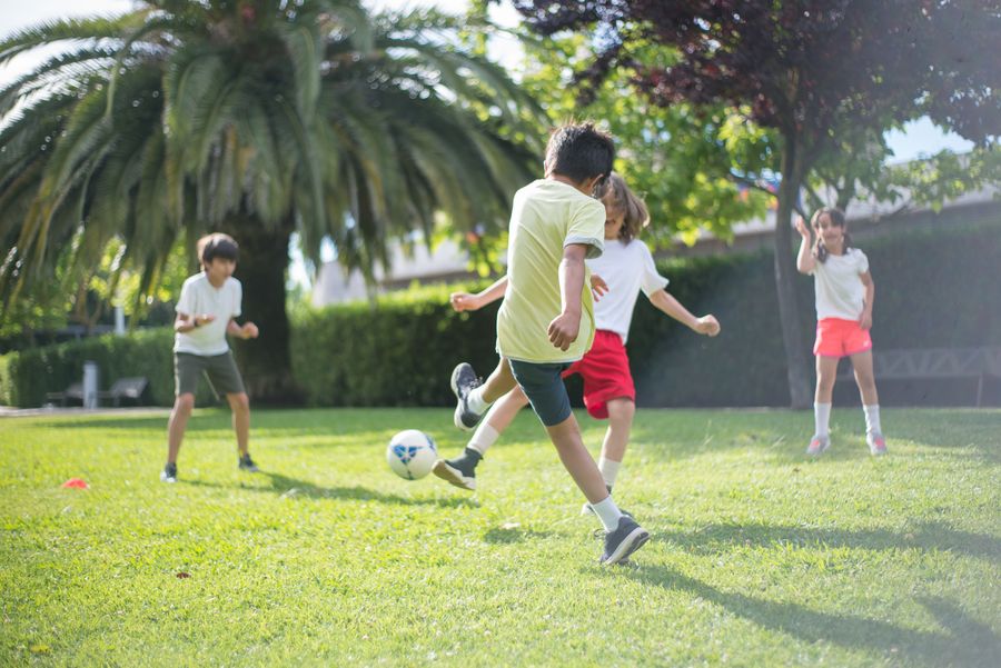 Chicos jugando al fútbol en una cancha comunitaria