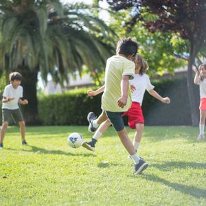 Children playing football on the grass in a sunny park