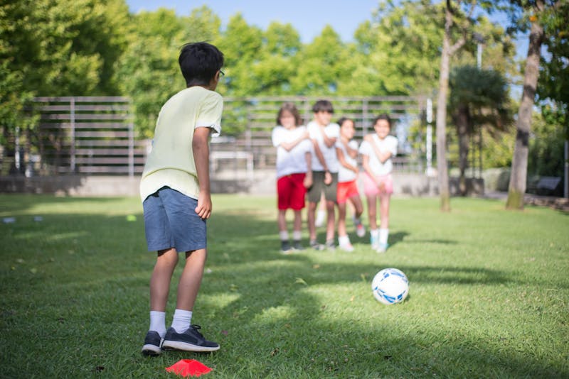 Children playing football together in a sunny outdoor park