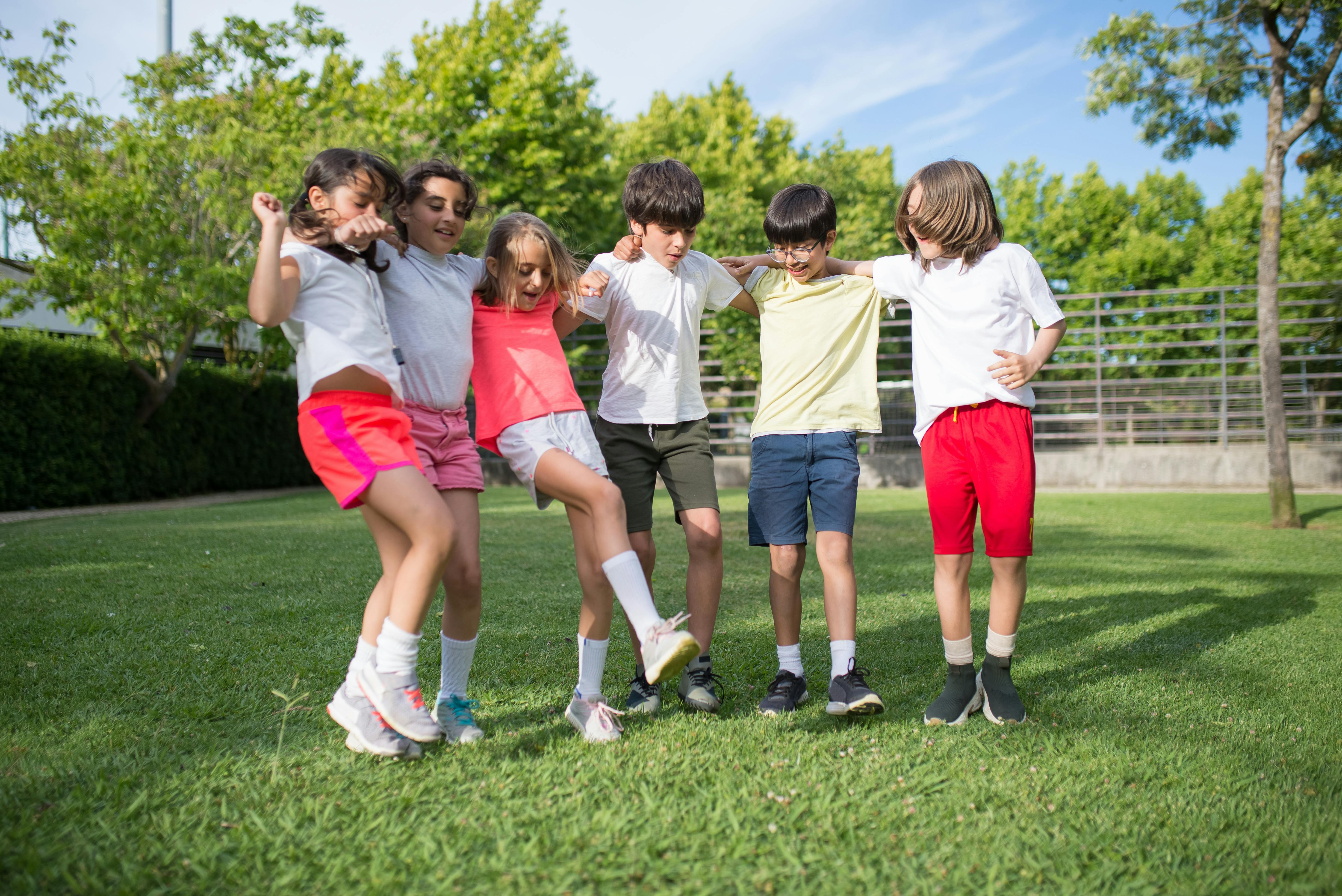 group of children standing on green grass field