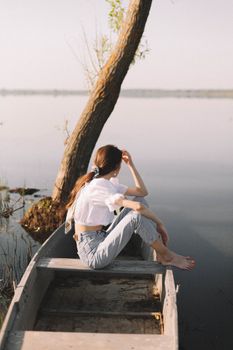A woman sits on a boat, enjoying a peaceful moment by a calm lake in Yaroslavl, Russia.
