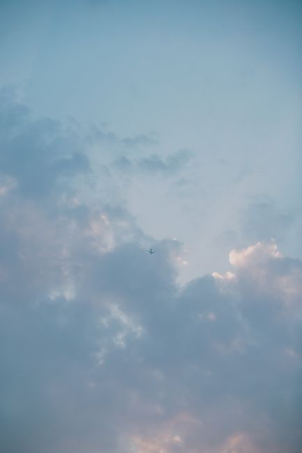 A peaceful sky with soft clouds and an airplane, captured against a serene backdrop.