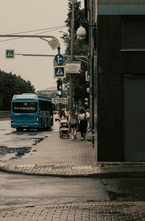 Free A blue electric bus drives on a wet street with pedestrians in a city. Stock Photo