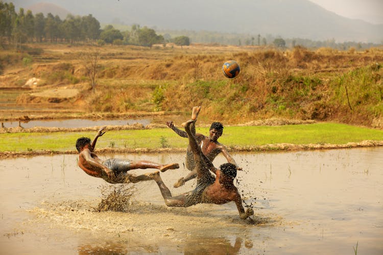 Men Playing Ball Sports On A Muddy Ground 