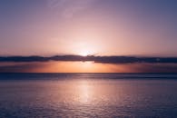 海面上，夕阳宁静地落下，色调温暖，海水平静