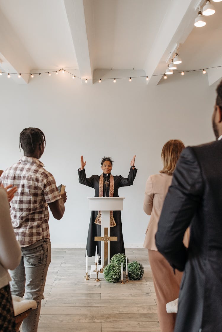 Pastor At A Podium With Her Hands Raised