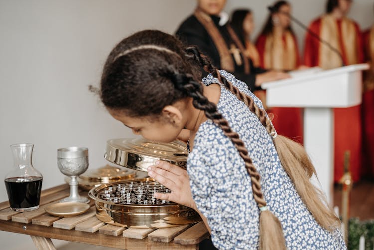 Girl In Floral Dress Looking At A Polished Stainless Steel Communion Ware