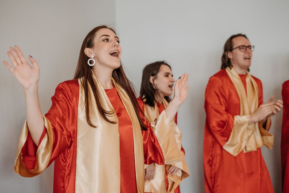 Three choir members wearing red and gold robes during performance`