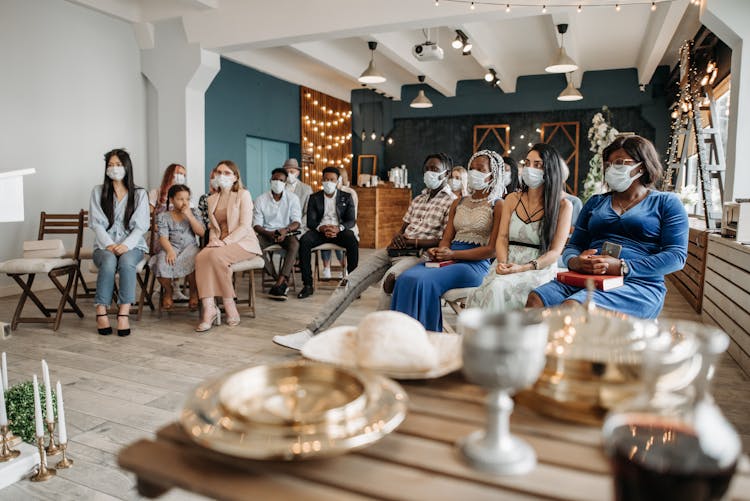 A Group Of People Wearing Face Mask While Sitting Inside The Church